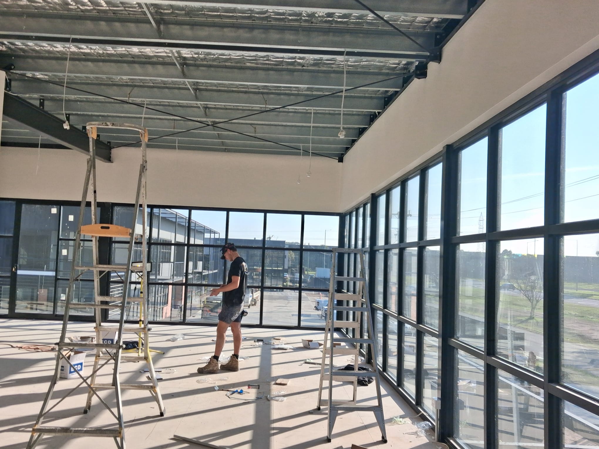 Open-plan floor with full-height glazing — mid-fitout, services in, walls going up.